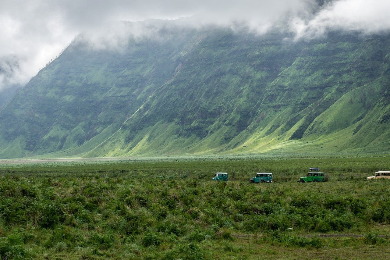 Hamparan savana kering dengan beberapa jeep wisata dan bukit berjajar di kawasan Bromo